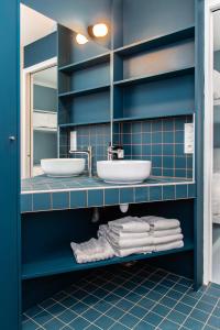 een badkamer met 2 wastafels, een spiegel en handdoeken bij OLDEGAR Hôtel in Nantes