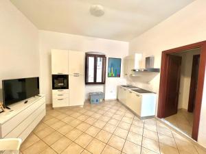 a large kitchen with white cabinets and a tv at Sardinian Gallery Corso in Bosa
