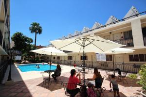 a group of people sitting at a table by a pool at Hotel El Camino Inn & Suites in Reynosa