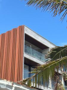 an external view of a building with a palm tree at Porto 2 Life Resort in Porto De Galinhas