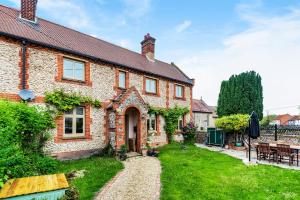 a brick house with a garden and a patio at Old School House in Burnham Market