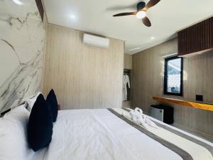 a bedroom with a white bed with a ceiling fan at Real Bungalow in Koh Rong