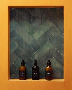 three bottles of soap sitting on a shelf in front of a wall at UNU Boutique Hotel -- Adults Only -- in Ahangama