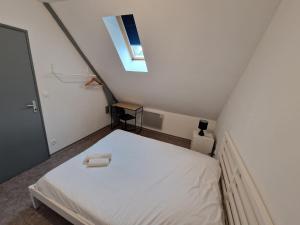 a small bedroom with a white bed with a window at Spacieux 3 chambres Tout équipé in Feignies +1 photo