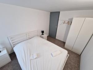 a bedroom with a white bed with two white cabinets at Spacieux 3 chambres Tout équipé in Feignies