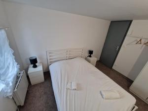 a bedroom with a white bed and two night stands at Spacieux 3 chambres Tout équipé in Feignies