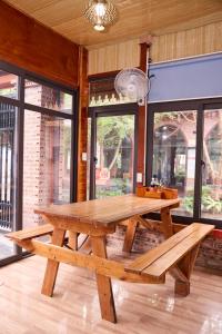 a wooden picnic table in a room with windows at Cosiana Homestay in Ninh Binh