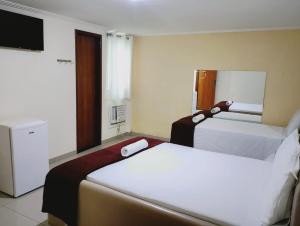 a hotel room with two beds and a television at Hotel Aliança in Salvador