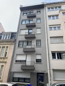 ルクセンブルクにあるLago Welcome Limpertsberg Suiteの側面にバルコニーがある高層ビル