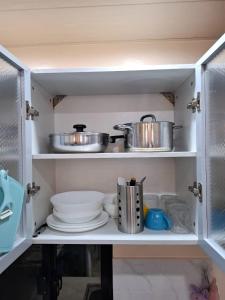 a kitchen cabinet with dishes and pots and pans at Bleu Saphire Apartments in Los Baños +28 photos