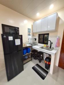 a kitchen with a black refrigerator and a sink at Bleu Saphire Apartments in Los Baños