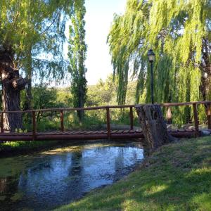 a wooden bridge over a river in a park at Don Andrés y doña cuca in Merlo