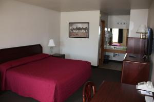 a hotel room with a red bed and a table at Boomtown Inn in Drumright