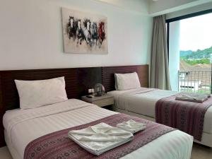 a hotel room with two beds and a window at Coco boutique hotel in Patong Beach
