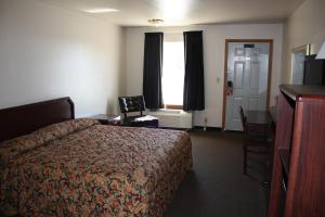 a hotel room with a bed and a desk at Boomtown Inn in Drumright