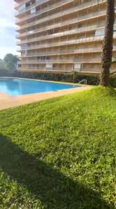 a building with a swimming pool next to a grass field at Horizonte al Mar in Miramar