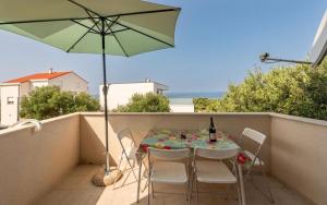 a table and chairs on a balcony with an umbrella at Apartmani Marina in Jakišnica