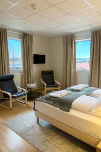 a bedroom with a bed and two chairs and a tv at T10 Self check-in Hotel in Hafnarfjördur