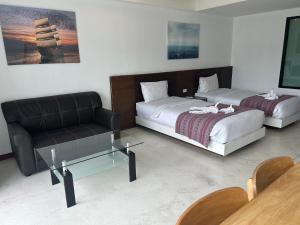 a room with two beds and a couch and a table at Coco boutique hotel in Patong Beach