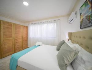 a bedroom with a large white bed and a window at Fully Equipped 2br Apt-dt5mins To The Beach in Sosúa +15 photos