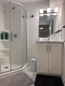 a white bathroom with a shower and a sink at Cozy and Spacious Suite - Private Ensuit Bath - King Bed - Ultra Fast Wifi - Free Parking - Smart TV in Rockland +14 photos