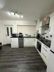 a white kitchen with white cabinets and appliances at Belexsia Guest House in Stoke on Trent