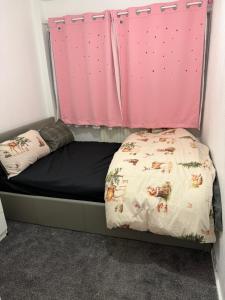 a bed in a room with a pink curtain at Belexsia Guest House in Stoke on Trent