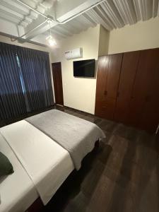 a bedroom with a bed and a flat screen tv at Fratello Hotel in Buga