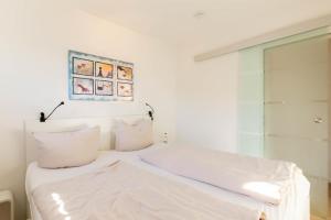 un lit blanc avec des draps et des oreillers blancs dans l'établissement Ferienwohnung Ostseerauschen 2, à Scharbeutz