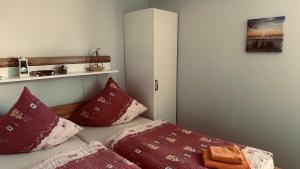 une chambre avec un lit aux oreillers rouges et une armoire dans l'établissement Ferienhaus Dittert, à Müritz