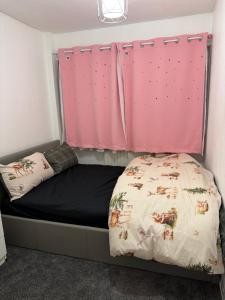 a bed in a room with a pink curtain at Belexsia Guest House in Stoke on Trent +12 photos