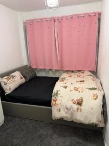 a bed in a room with a pink curtain at Belexsia Guest House in Stoke on Trent