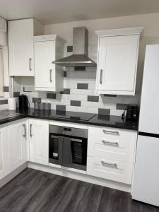a kitchen with white cabinets and a stove top oven at Belexsia Guest House in Stoke on Trent