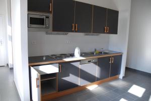 a kitchen with black cabinets and a sink and a microwave at Szent Jakab Vendégház in Pannonhalma