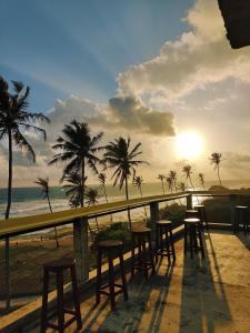 una fila de taburetes en un balcón con vistas a la playa en The Sun Set, en Weligama 15 fotos más