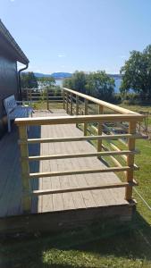 a wooden deck with a bench on the grass at Lovely tiny house with a dream view ! 
