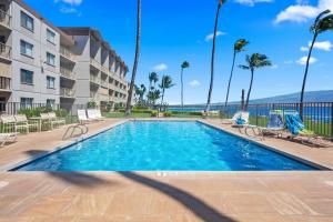 a swimming pool at a resort with palm trees and chairs at Maalaea Kai 311 - Direct Ocean Front, Split AC in Wailuku