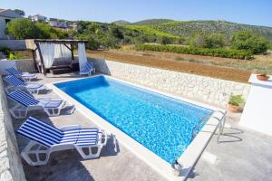 een zwembad met ligstoelen en een zwembadvisor bij Apartments with a swimming pool Gustirna, Trogir - 11703 in Marina