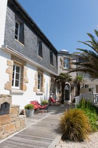 a house with a wooden deck in front of it at Hôtel La Baie des Anges, son SPA marin & sa piscine couverte et chauffée in Landéda