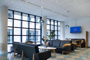 a waiting room with couches and tables and windows at Hotel Frederikshavn in Frederikshavn