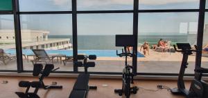 ein Fitnessstudio mit Blick auf ein Schwimmbad und Menschen in der Unterkunft Infinity ApartHotel Boutique - Gym Roof Top & Spa in Mamaia Nord – Năvodari