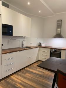 a kitchen with white cabinets and a wooden floor at Villa Alexandra 1897 Wohnung Vilma in Bad Wildungen +8 photos