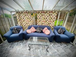 a living room with blue couches and a glass table at Modern-privateGarden-Family-20MinToLDN in Stevenage