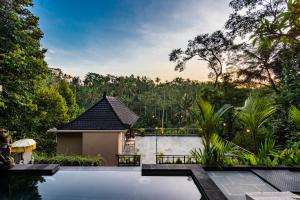 a swimming pool in front of a house at Ellena Resort Tegallalang by Dhananjaya Hospitality in Tampaksiring
