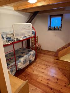 a room with bunk beds and a window and wooden floors at La Casetta del Picchio in Caspoggio