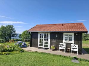 a small black shed with two chairs and flowers at Lovely tiny house with a dream view ! in Østdal