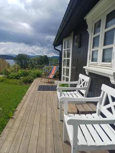 two white benches sitting on a wooden deck at Lovely tiny house with a dream view ! 