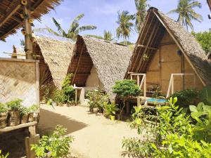 un grupo de cabañas con árboles y plantas en Amwani Beach Camp, en El Nido