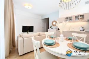 a white living room with a table and a couch at Apartament na klifie - Łukęcin in Łukęcin