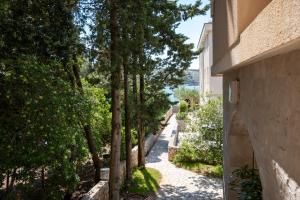 ein Weg zwischen zwei Gebäuden, gesäumt von Bäumen in der Unterkunft Apartments by the sea Stara Novalja, Pag - 21662 in Stara Novalja